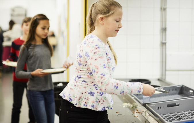 Barn som lämnar disk i en diskstation i en skolmatsal.